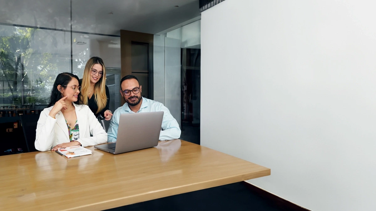 Equipo de trabajo colaborando en una tarea usando una laptop